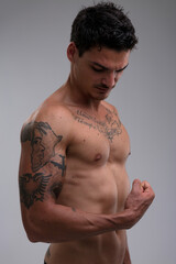 Handsome, muscular, tattooed man observes flexed bicep