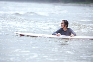 Pre-teenage girl has fun with the surfboard in the sea, outdoor water sport activity in surfing