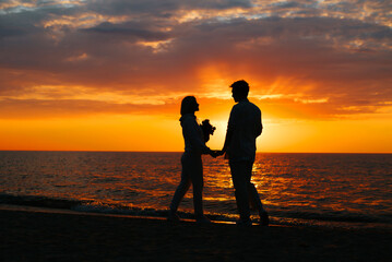 Romance, silhouette boyfriend and girlfriend holding hands together at sea at sunset. Couple in love date on the seashore