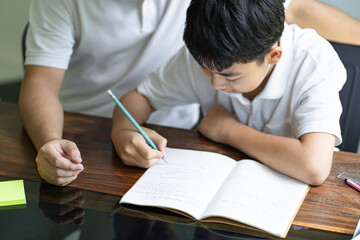 Asian father helps son to do her homework for the school..child study together homeschooling concept getting homework help from father