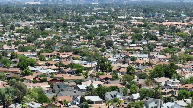 Sprawling neighborhoods in suburb of large American city. Aerial tilt up reveal of urban skyline. Houses and homes in southwest USA housing developments.