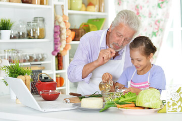 Senior man with granddaughter preparing dinner