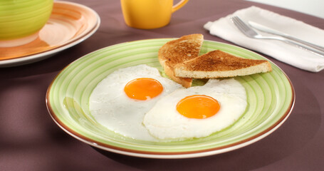 fried eggs with toast on a green plate. close-up. angle view. camera tracking. colored background. traditional breakfast. sunny day.