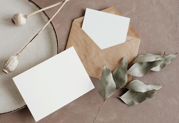 Cards mockup, envelopes and dried flowers and leaves top view on beige textured background with copy space. flatlay. Blank, greeting card template. © irenastar