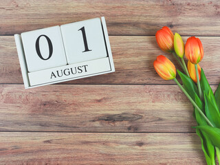 flat lay of wooden calendar with date August 01 on wooden table background with orange and yellow...