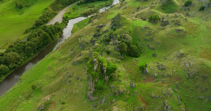 Geological rock features sticking out from grass hill in New Zealand, aerial
