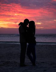 Couple, sunset and silhouette outdoor at the beach with love, care and commitment. Romantic man and woman hug or affectionate on vacation, holiday or nature travel adventure with sunrise sky on date