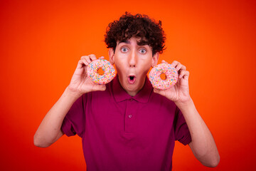 Young attractive guy eats pink donuts. Delicious breakfast and good vibes.