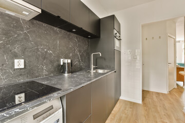 a kitchen with black and white marble on the counter tops, along with an open door leading to another room