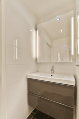 a white bathroom with black tile flooring and walls in the shower area, there is a mirror on the wall above the sink