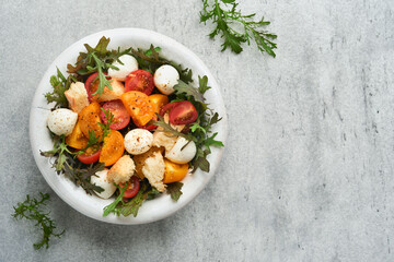 Tuscan Panzanella. Cherry Tomatoes salad with arugula, basil, mozzarella and bread crackers on white bowl. Traditional italian salad. Mediterranean healthy food and