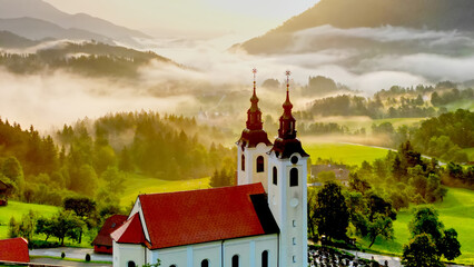 Aerial drone view of small beautiful church on valley in Slovenia at dawn. Beautiful summer morning...