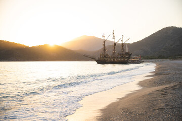 a large ship is docked at the seashore at sunset and beautiful mountains