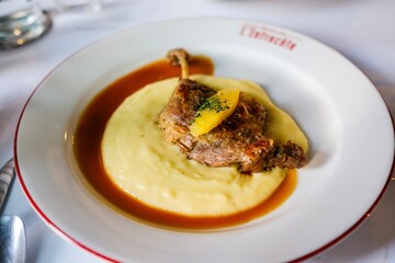 A plate of canard a l’orange (orange duck) — confit duck leg with potato puree and orange sauce — at a French bistro in Circular Quay, Sydney. New South Wales, Australia