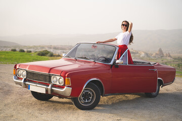 beautiful happy girl in a skirt posing near a retro car in the mountains of cappadocia