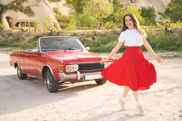 beautiful happy girl in a skirt posing near a retro car in the mountains of cappadocia