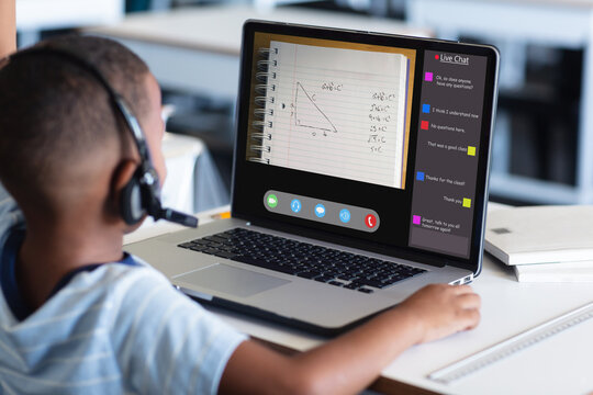 Rear View Of African American Boy Wearing Headphones Using Laptop And Studying At Home