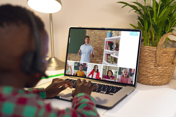 African american boy having a video conference with male teacher and diverse students on laptop