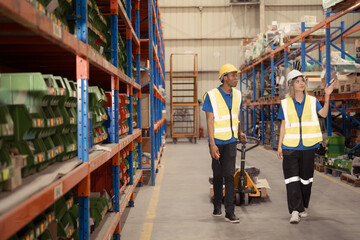 Two warehouse workers pushing a pallet truck in a shipping and distribution warehouse.