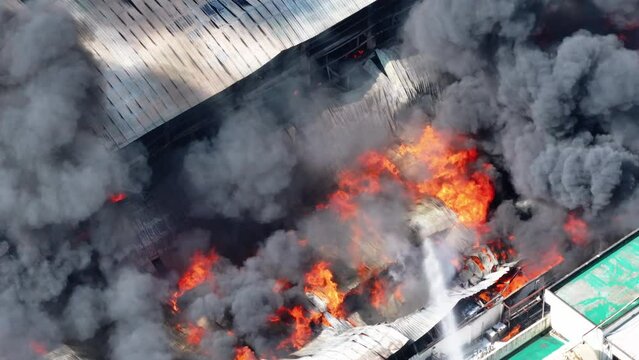 Aerial view of Fire in industrial building. Multi-storey concrete hangar with flames. 