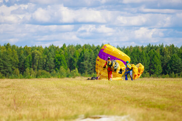 Landing skydivers-athletes with a parachute on the ground.