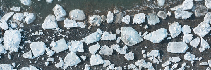 Top view of the ice floes on the shore. Aerial view of melting ice on the sea coast. Climate change in the Arctic. Northern nature. Wide panoramic background.