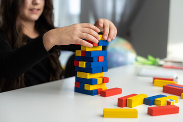 Children building wood blocks at playground. Girl kid playing stacking wood blocks (Jenga games) for meditation practice. Hand movement control Building Computational Skills Children's play concept.