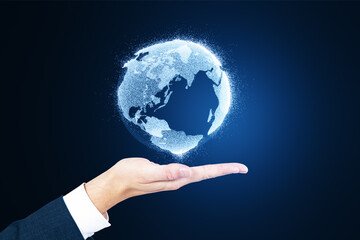 Close up of man's hand holding glowing globe hologram on blurry blue background. Digital earth and metaverse concept.