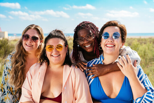 Group of plus size women with swimwear at the beach - Multiethnic curvy adult female having fun and sunbathing on summertime vacation, concepts about beauty, body positivity and self acceptance - Powered by Adobe
