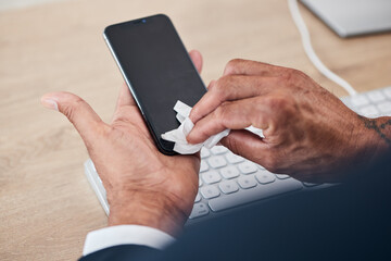 Closeup of man wipe his phone with a tissue to prevent germs, bacteria or dirt in his office. Technology, hands and male person cleaning cellphone screen for hygiene, health and wellness at workplace