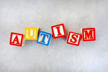 Autism spelled out in kids building blocks on mottled grey.