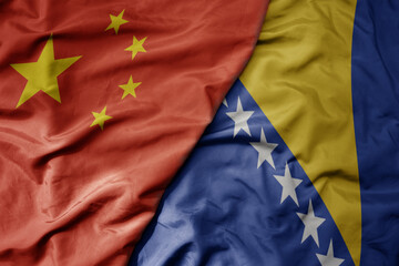 big waving national colorful flag of china and national flag of bosnia and herzegovina .
