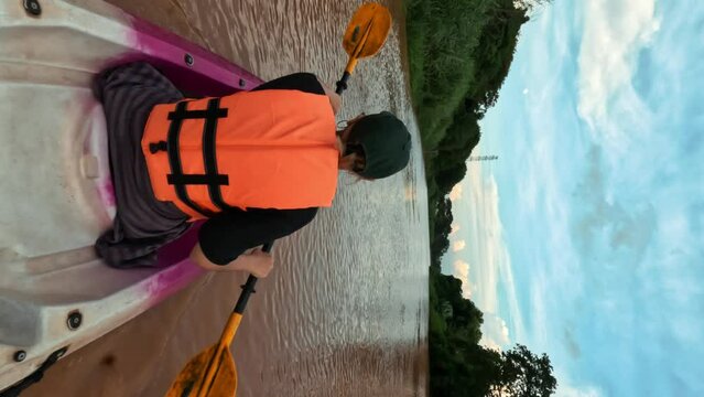 Young woman rowing in kayak summer trip 4K active lifestyle kayaking concept vertical footage, Thailand.
