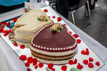 Romantic wedding Two cakes in heart shape, roses bouquet on white table background. Top view