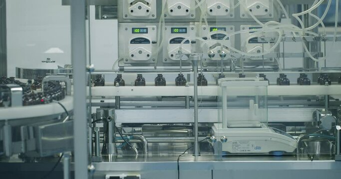 Robotic arm put medicine package on conveyor belt. Packaged goods at automated production line. Medical factory assembly line packing medicine machine. Production line of pharmaceutical manufacturing.