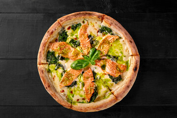 Pizza with cheese, salmon and spinach dressed with pesto and fresh basil