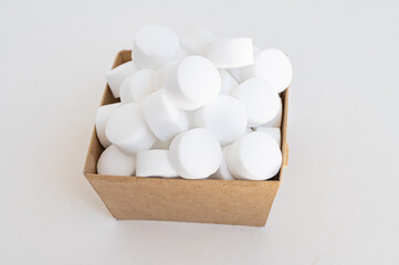 White pressed salt tablets for the dishwasher close-up in a box. Place for text