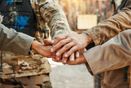 Paintball, team and hands together for meeting in motivation, huddle or game plan on the battle field. Group of paintballers piling hand for teamwork, unity or collaboration in goals, mission or war