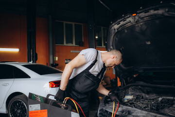 Male car mechanic filling up car air conditioner and check the compressor oil system caused by the...