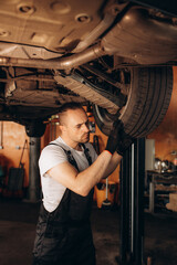 Fototapeta na wymiar Mechanic working under car in auto repair shop