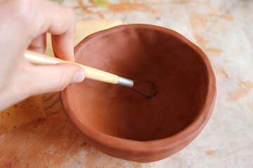Woman's hand molding a clay bowl