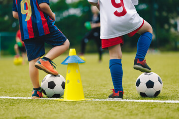 Two elementary-age children on football training. Little boys in colorful soccer jersey uniforms playing on the football pitch. Sports training equipment for kids