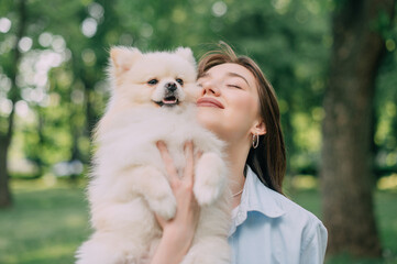Portrait of a young woman with her dog. Pomeranian in the hands of his owner.