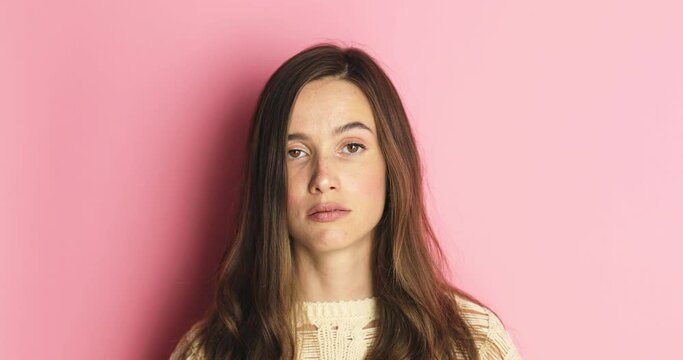 A displeased young woman rolls her eyes isolated over pink background. Caucasian lady in displeasure, she is tired of situation, thinks how cant you still not understand.