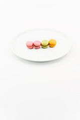 Fototapeta na wymiar immagine primo piano di soffici macarons su piatto in porcellana bianca, vista dall'alto su superficie bianca