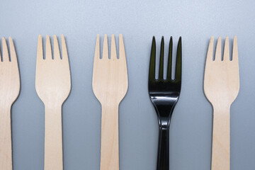Plastic and wooden forks on a gray background. Save the ecology.