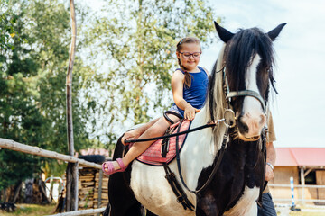 Cute girl on a red horse outdoor. Hippotherapy for young children with down syndrome, therapy after...