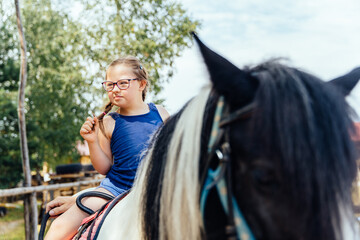 Little cute girl walking with a pony in manege at open air outdoor. Human and horse friendship,...