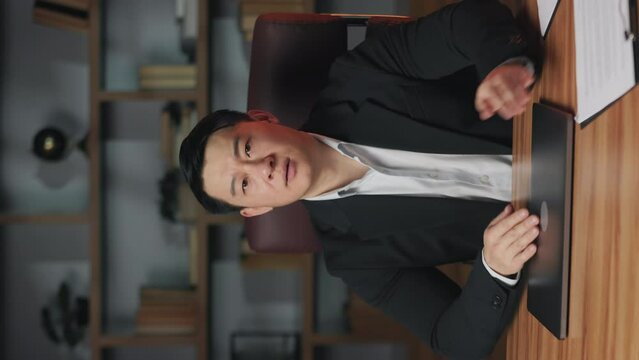Vertical video of upset asian entrepreneur forming x with hands after shutting down laptop in office. Displeased business person stopping internal misuse of company's resources by employees.