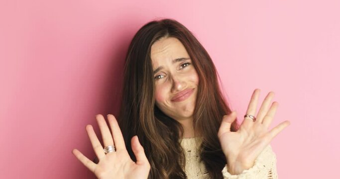 Pretentious brunette woman in knit sweater pointing fingers to camera and next laugh on pink background. Girl laughing with a grin, sarcasm, sarcastically, ask you no, not you, i not choice you!